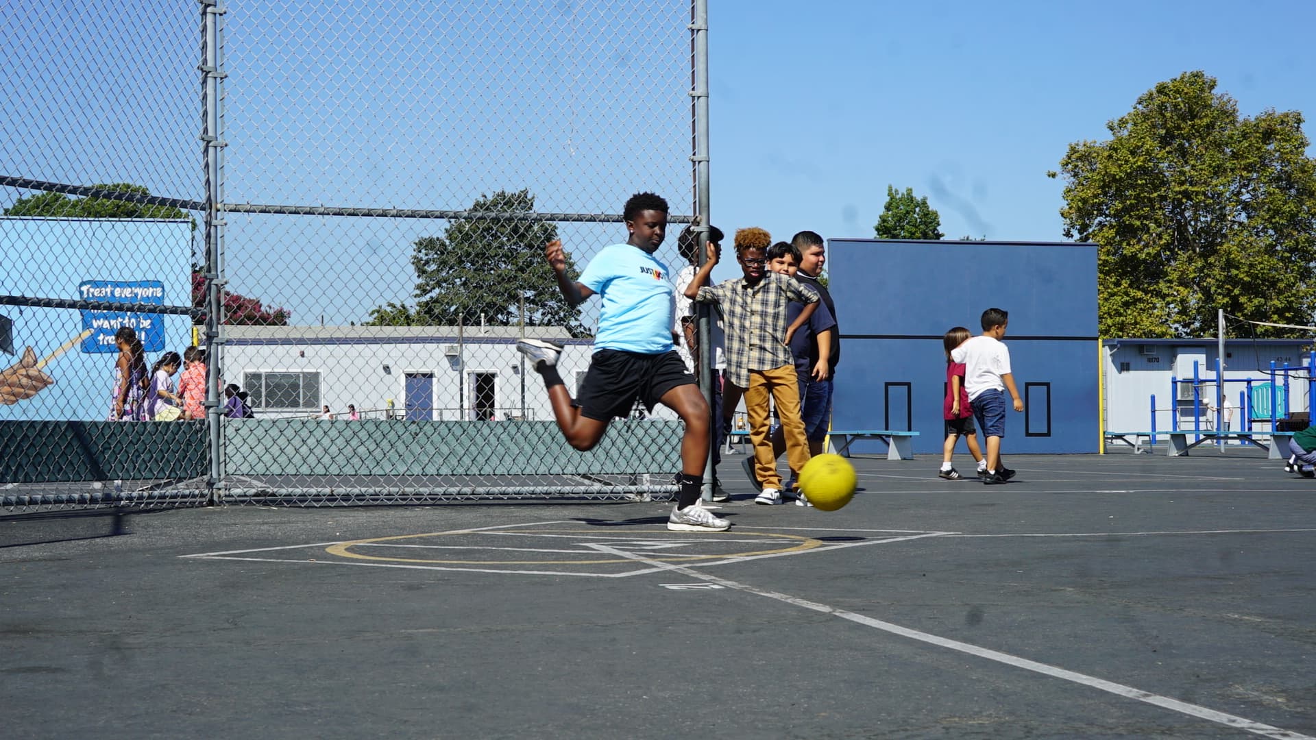 Students playing kickball on school playground with CF Fitness coach